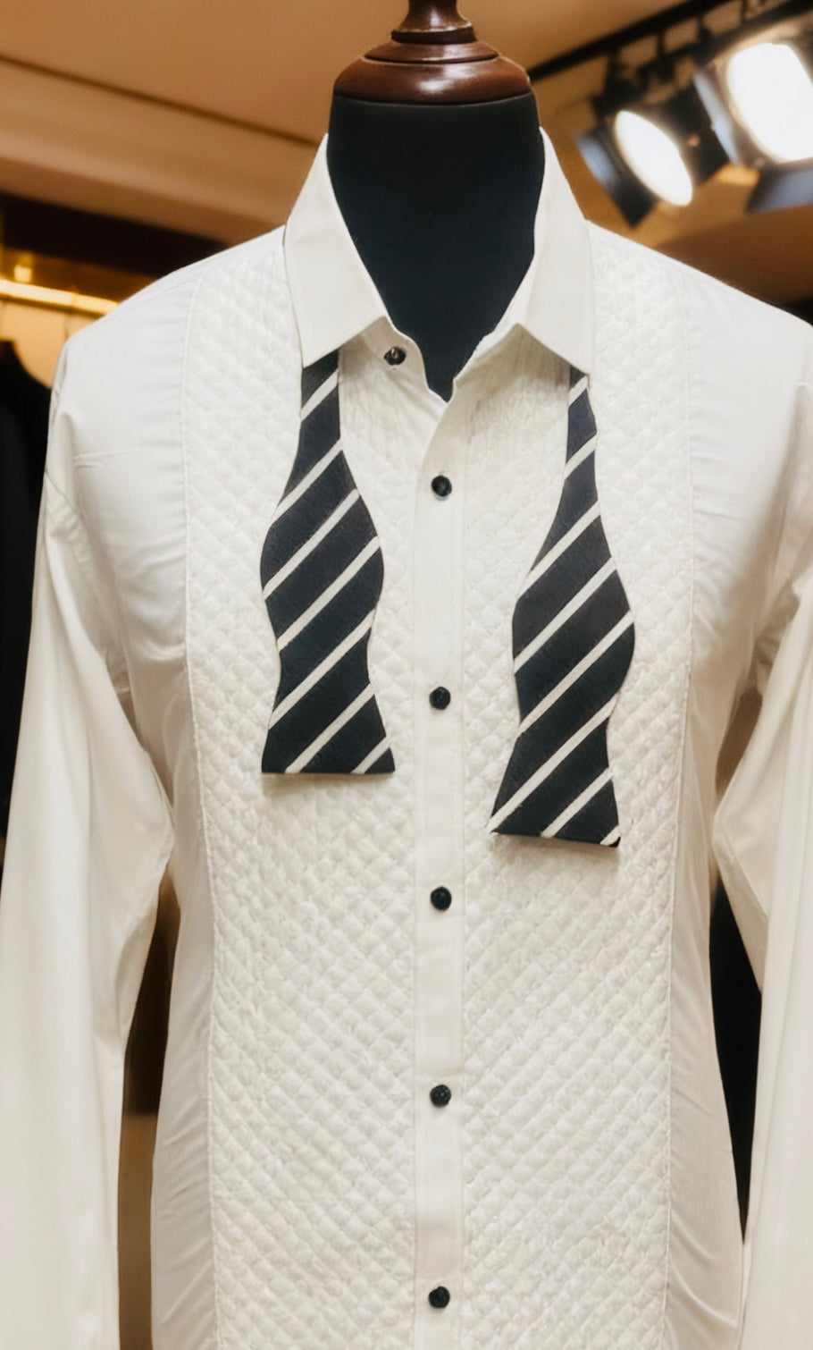 White textured shirt with black and white striped vest on a mannequin in a store setting.
